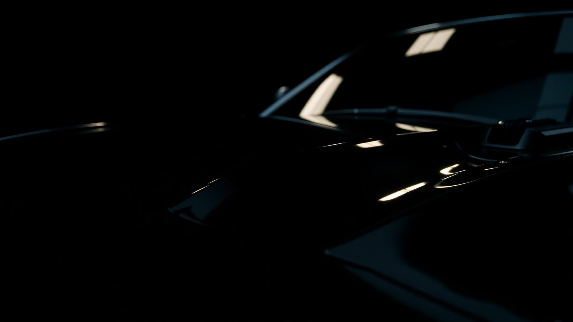 Freshly detailed glossy black car hood reflecting showroom light